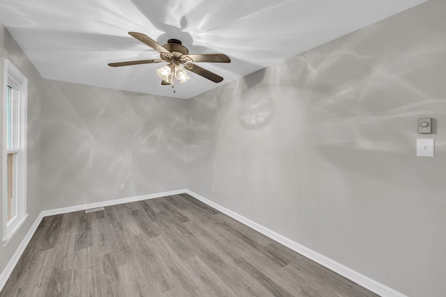 empty room with baseboards, a ceiling fan, and wood finished floors