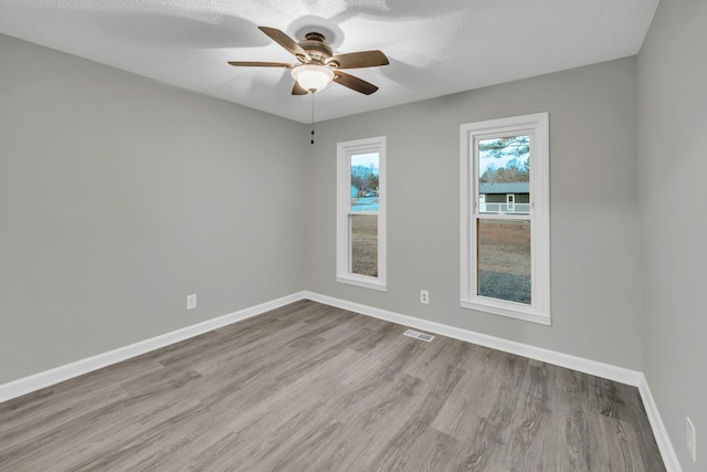 empty room featuring baseboards, wood finished floors, visible vents, and a ceiling fan
