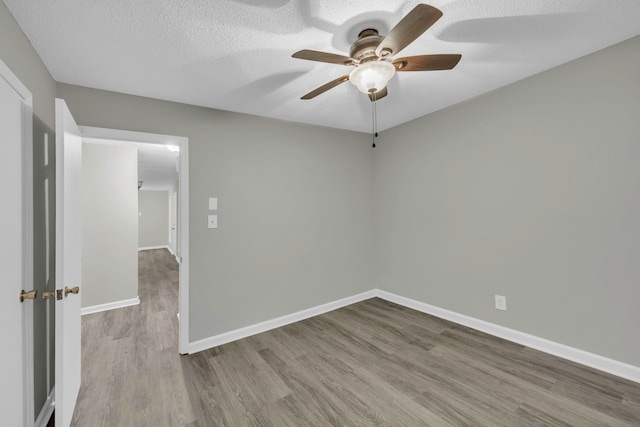 unfurnished room with baseboards, a ceiling fan, wood finished floors, and a textured ceiling