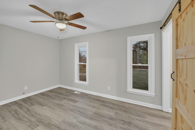 empty room featuring wood finished floors, baseboards, and a barn door