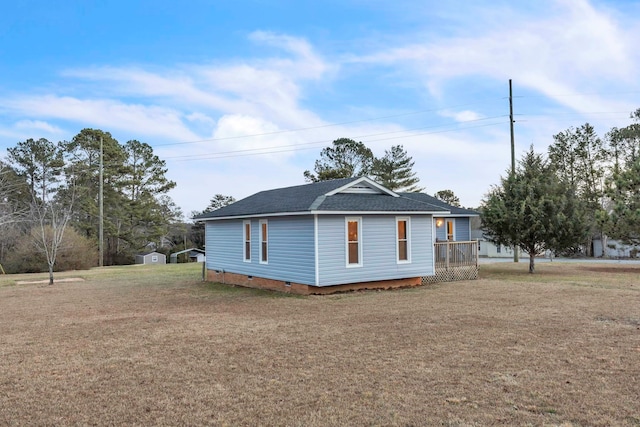 view of side of property featuring a storage shed, an outbuilding, roof with shingles, a lawn, and crawl space