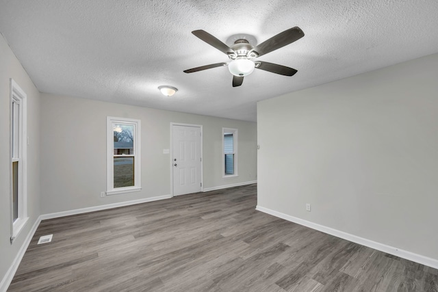 spare room with baseboards, a ceiling fan, wood finished floors, and a textured ceiling