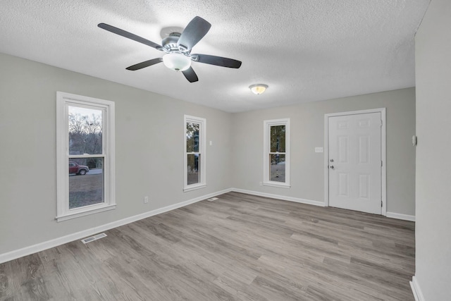 empty room featuring wood finished floors, a textured ceiling, and baseboards