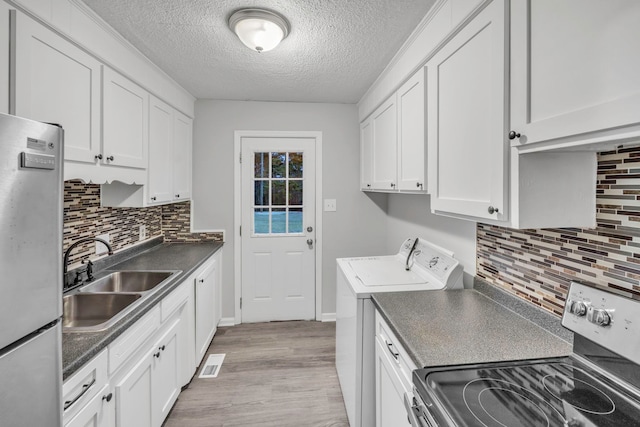 kitchen featuring stainless steel appliances, a sink, a textured ceiling, dark countertops, and visible vents