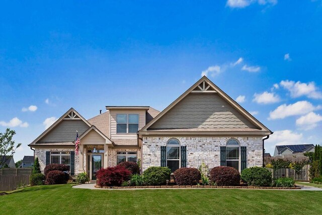 craftsman-style home featuring brick siding, a front yard, and fence