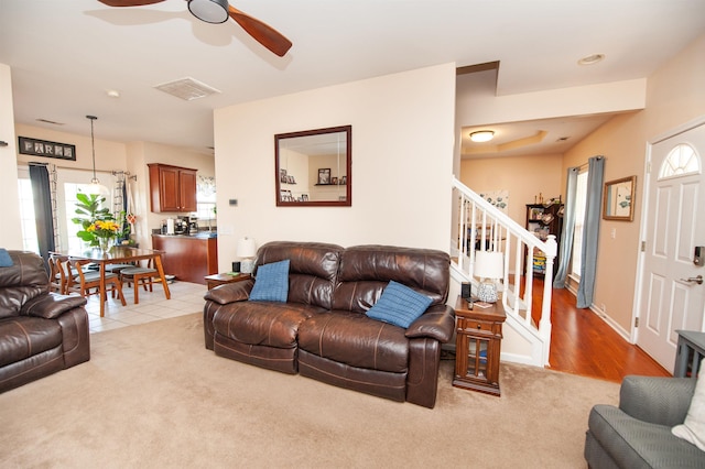living room with visible vents, carpet floors, stairs, and ceiling fan