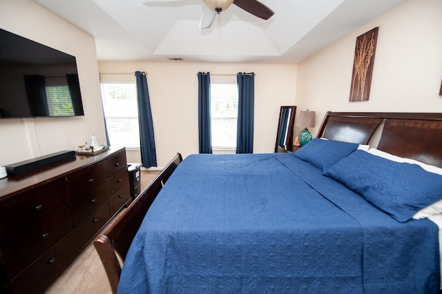 bedroom with a ceiling fan, multiple windows, a tray ceiling, and visible vents