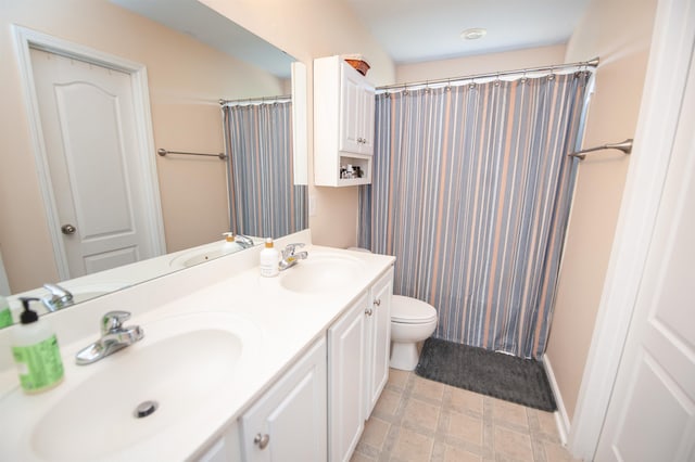 full bath featuring a sink, a shower with shower curtain, double vanity, and toilet