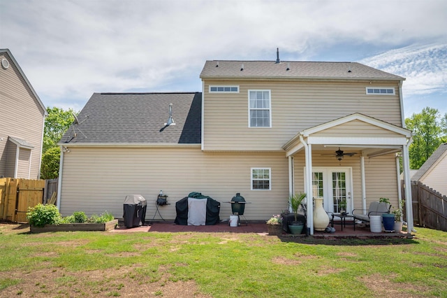 rear view of property featuring fence, ceiling fan, a lawn, and a patio