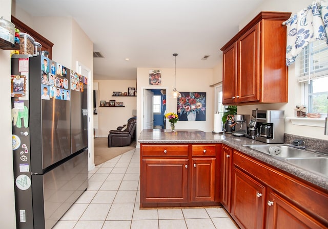 kitchen featuring a peninsula, freestanding refrigerator, dark countertops, and light tile patterned floors