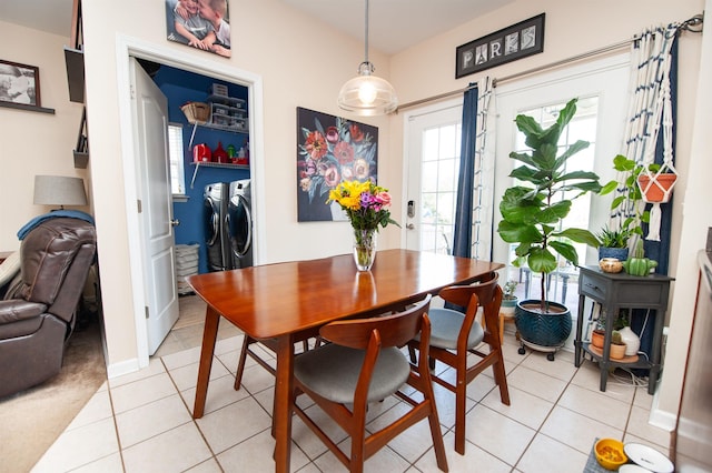 dining room featuring separate washer and dryer, baseboards, and light tile patterned floors