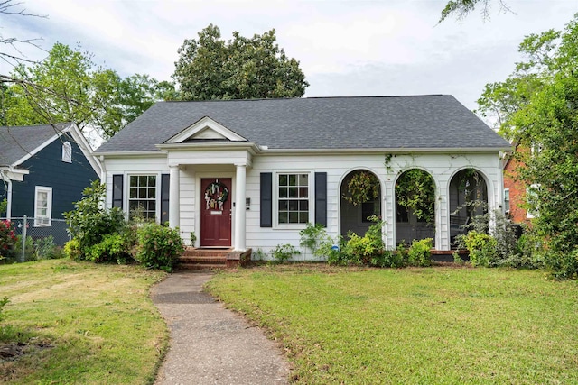 view of front of home featuring fence, a shingled roof, and a front yard