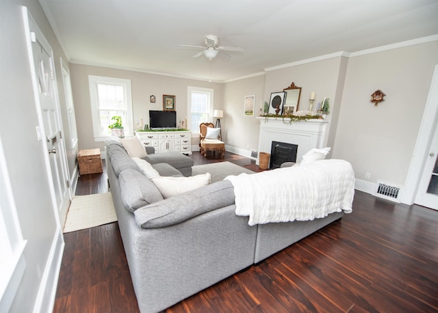 living area with visible vents, a ceiling fan, wood finished floors, a fireplace, and ornamental molding