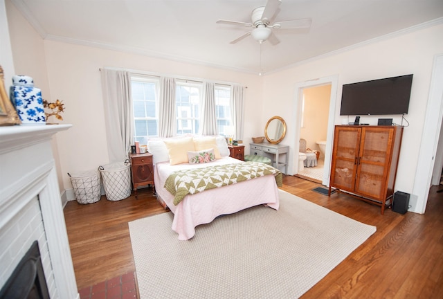 bedroom featuring a fireplace with flush hearth, ceiling fan, crown molding, and wood finished floors