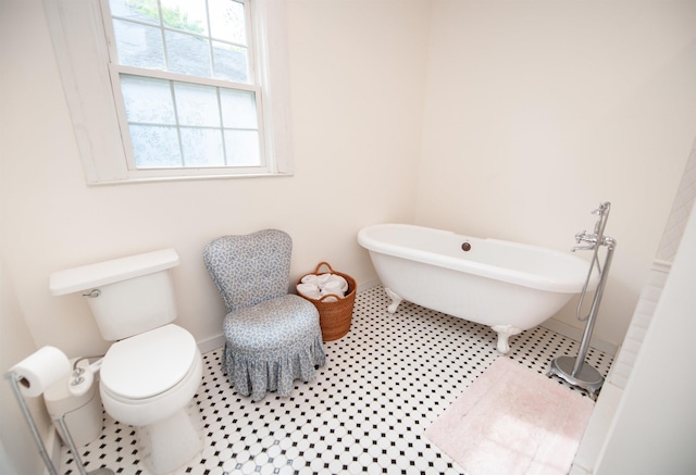 full bath featuring a soaking tub, tile patterned floors, baseboards, and toilet