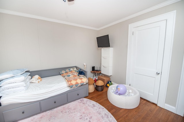 bedroom with wood finished floors and ornamental molding
