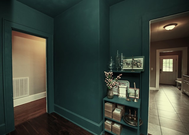 corridor featuring baseboards, wood finished floors, and visible vents
