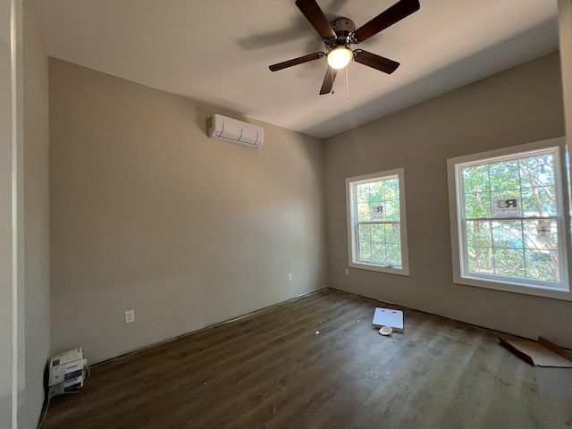 empty room with ceiling fan, wood finished floors, and a wall unit AC