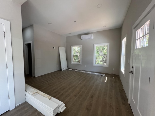 unfurnished living room with dark wood-style floors and a wall unit AC