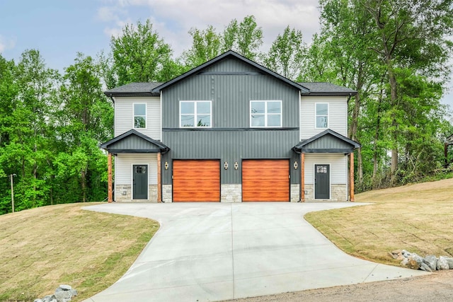 view of front facade featuring stone siding, a front lawn, driveway, and a garage