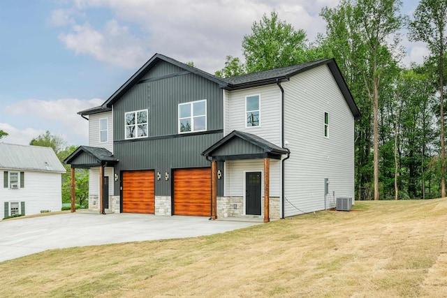 view of front of property featuring driveway, stone siding, central AC, a garage, and a front yard