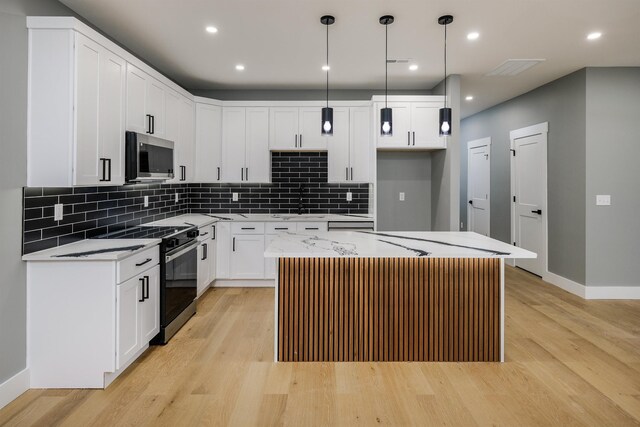 kitchen with light wood finished floors, a sink, stainless steel microwave, baseboards, and electric range oven