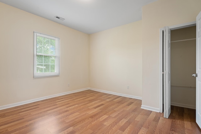 unfurnished bedroom featuring visible vents, a closet, light wood-style flooring, and baseboards