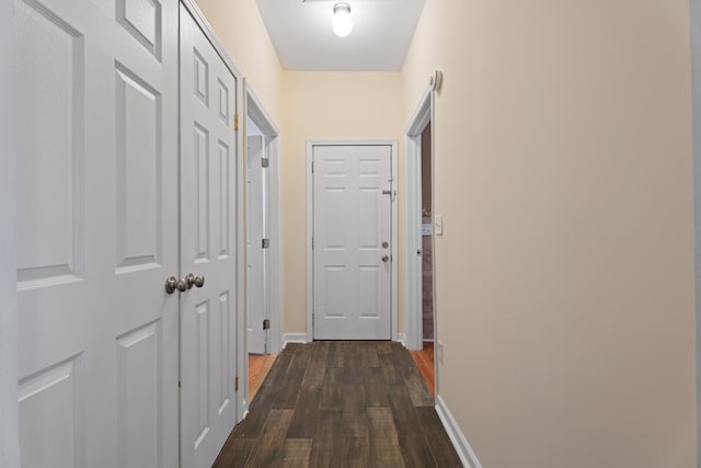 hallway featuring dark wood-style floors and baseboards