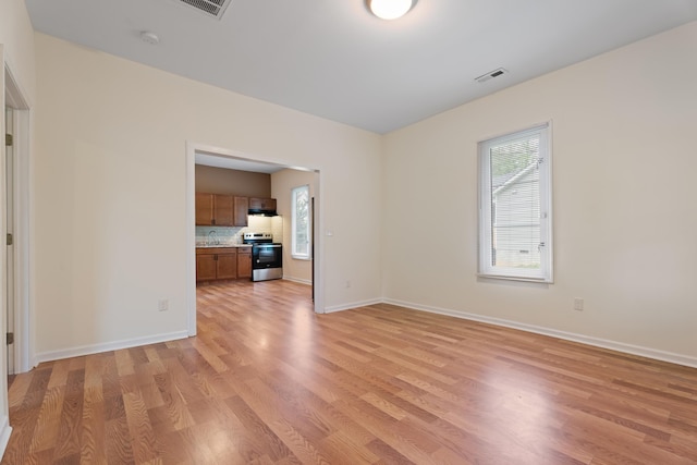 empty room featuring visible vents, light wood-style flooring, and baseboards
