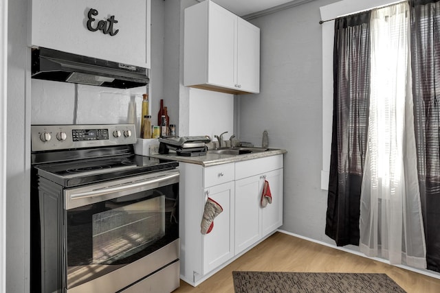kitchen featuring light wood-style floors, under cabinet range hood, stainless steel electric range, a sink, and white cabinetry