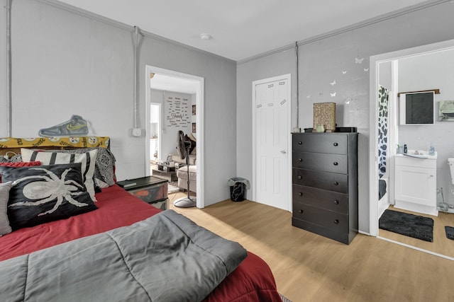 bedroom with wood finished floors and connected bathroom