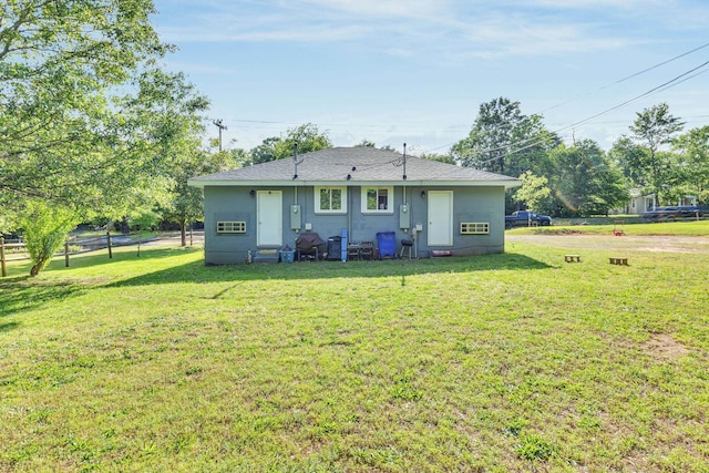 back of house featuring roof with shingles and a yard