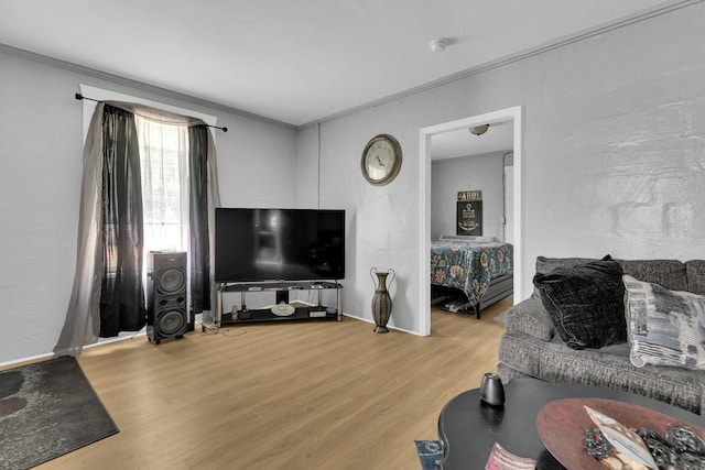 living room featuring wood finished floors, ornamental molding, and baseboards