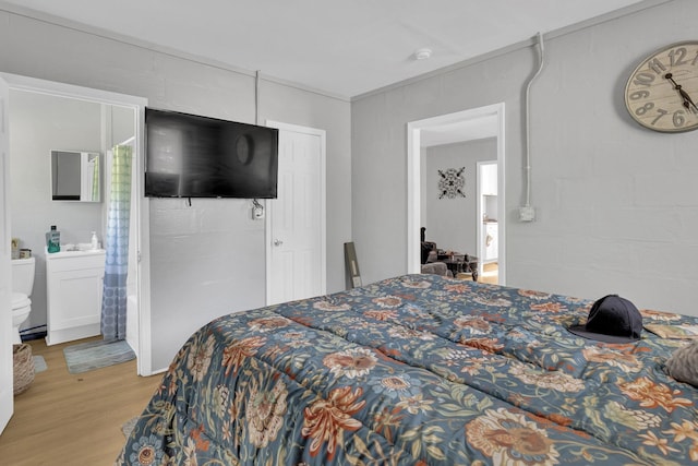 bedroom with wood finished floors and connected bathroom