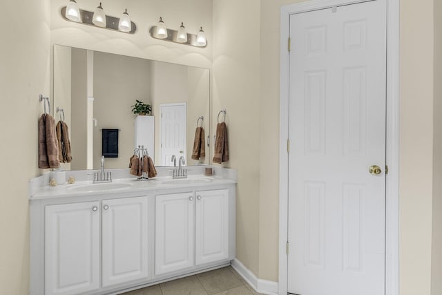 full bath with baseboards, tile patterned flooring, double vanity, and a sink