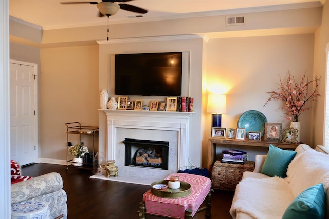 living room featuring visible vents, a high end fireplace, ornamental molding, wood finished floors, and a ceiling fan