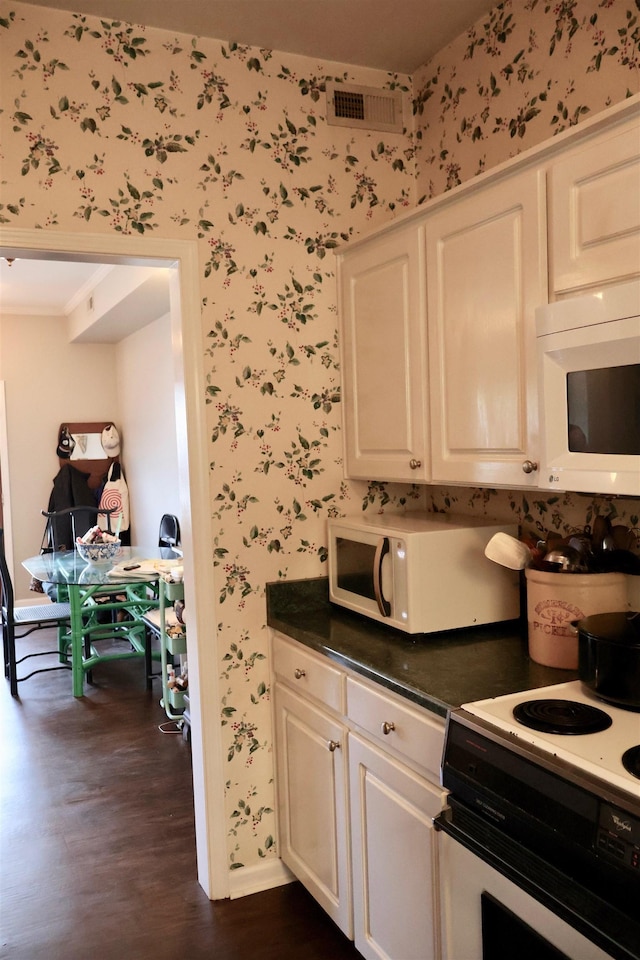 kitchen with white appliances, dark wood-type flooring, visible vents, baseboards, and wallpapered walls