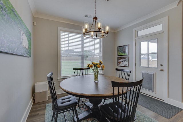 dining area featuring crown molding, visible vents, baseboards, an inviting chandelier, and wood finished floors