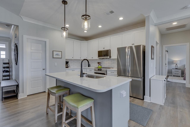 kitchen featuring tasteful backsplash, appliances with stainless steel finishes, light wood-type flooring, a sink, and visible vents