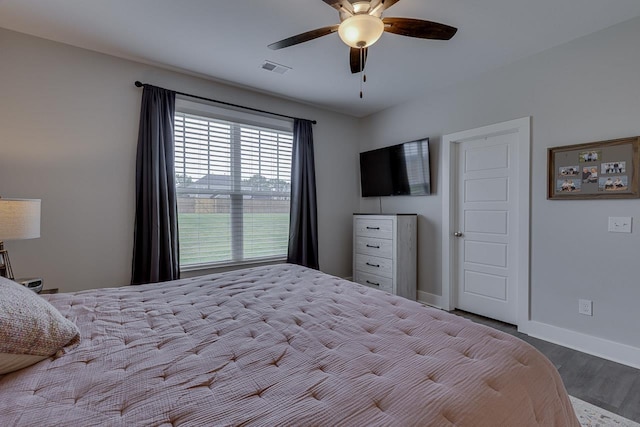 bedroom featuring wood finished floors, a ceiling fan, visible vents, and baseboards