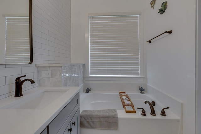 bathroom with a bath, vanity, and decorative backsplash