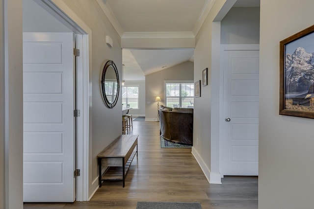 hall with ornamental molding, vaulted ceiling, wood finished floors, and baseboards