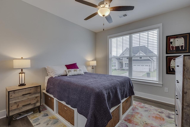 bedroom with baseboards, visible vents, wood finished floors, and multiple windows