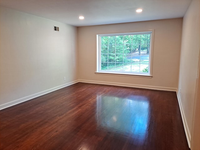 empty room featuring recessed lighting, visible vents, dark wood-style flooring, and baseboards