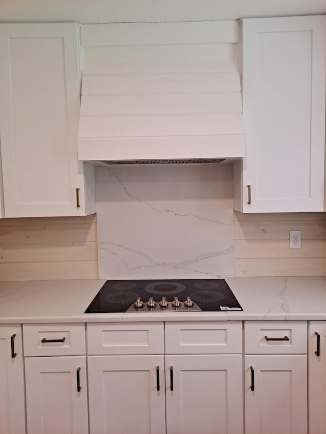 kitchen featuring premium range hood, white cabinetry, black electric stovetop, and decorative backsplash