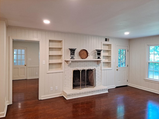 unfurnished living room featuring dark wood finished floors, built in features, and a fireplace