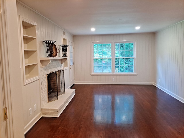 unfurnished living room featuring dark wood-style floors, baseboards, built in features, and a brick fireplace