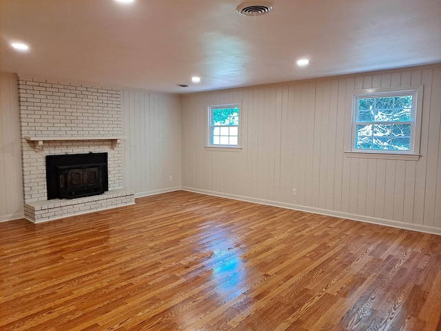 unfurnished living room featuring a fireplace, wood finished floors, and visible vents