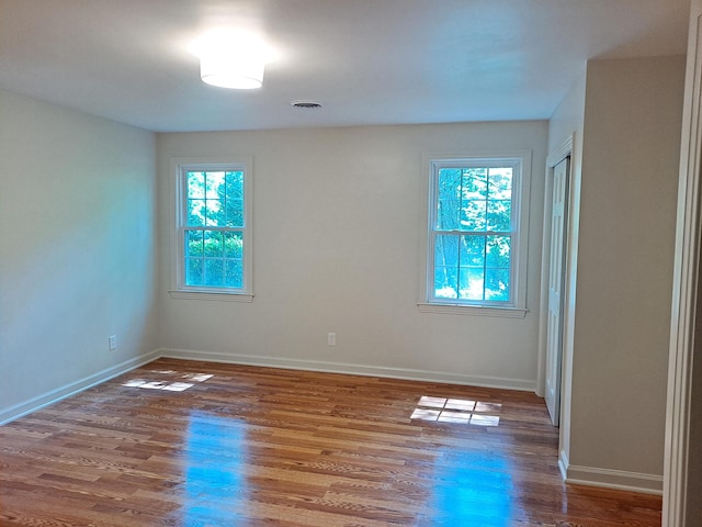 spare room with visible vents, baseboards, wood finished floors, and a healthy amount of sunlight