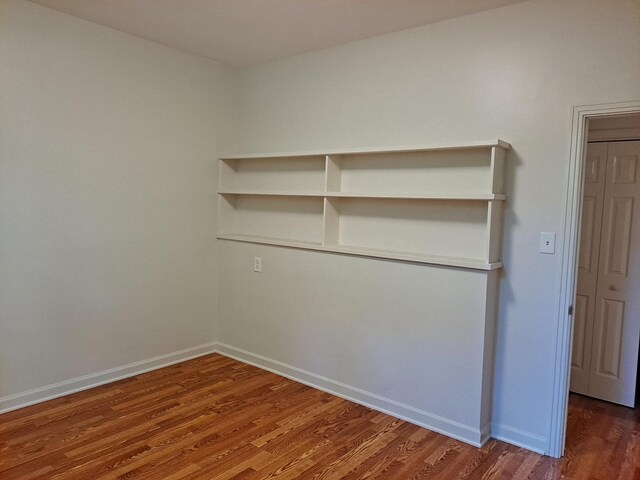 spare room with baseboards and wood finished floors